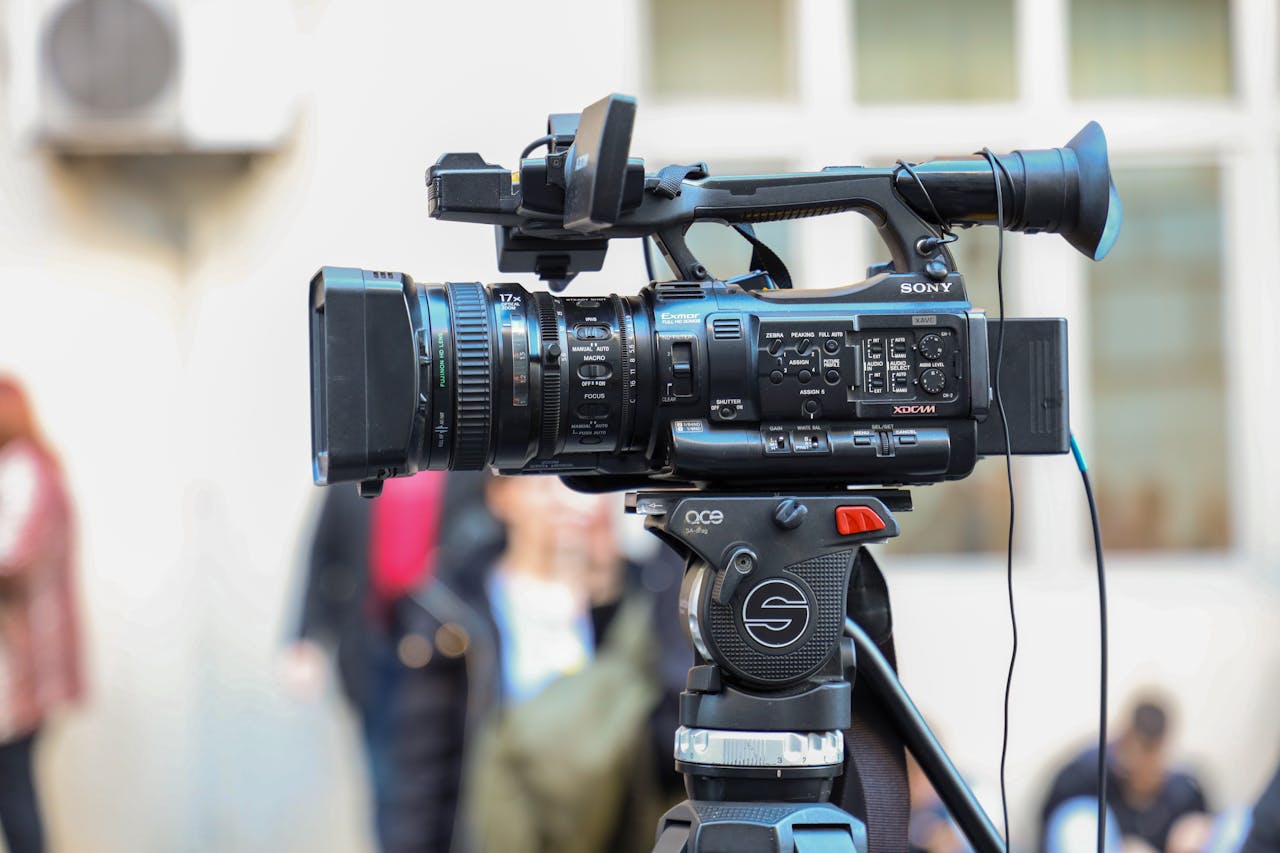 Close-up of a Sony video camera mounted on a tripod for outdoor filming.