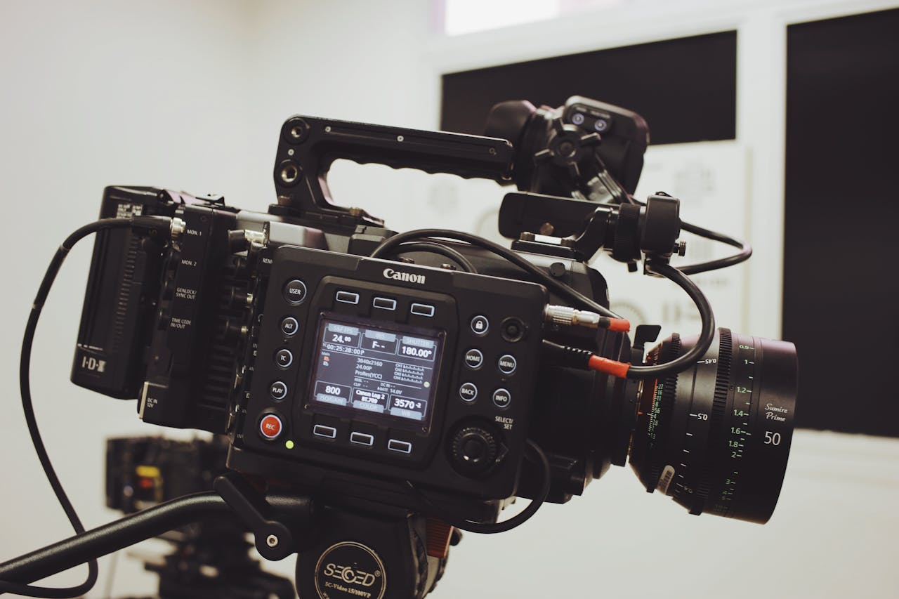 menu-02 Close-up of a professional video camera setup on a tripod, ready for filming in a studio environment.