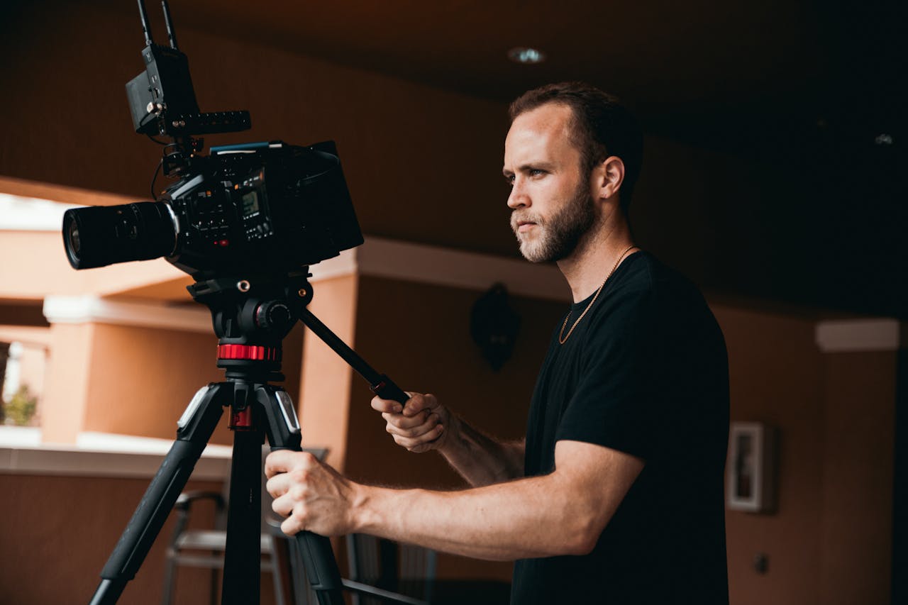 menu-05 Professional cameraman adjusting camera on tripod in a studio setting.